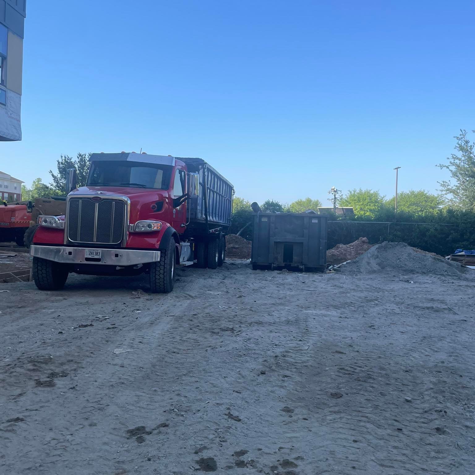 Dogwood Disposal red Peterbilt roll-off truck delivering dumpster in Statesboro Georgia